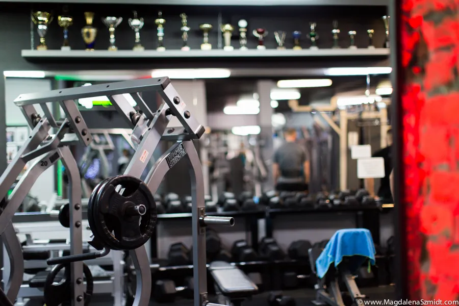 Wnętrze siłowni Słodkiewicz Gym — maszyna Hammer Strength i półka z pucharami